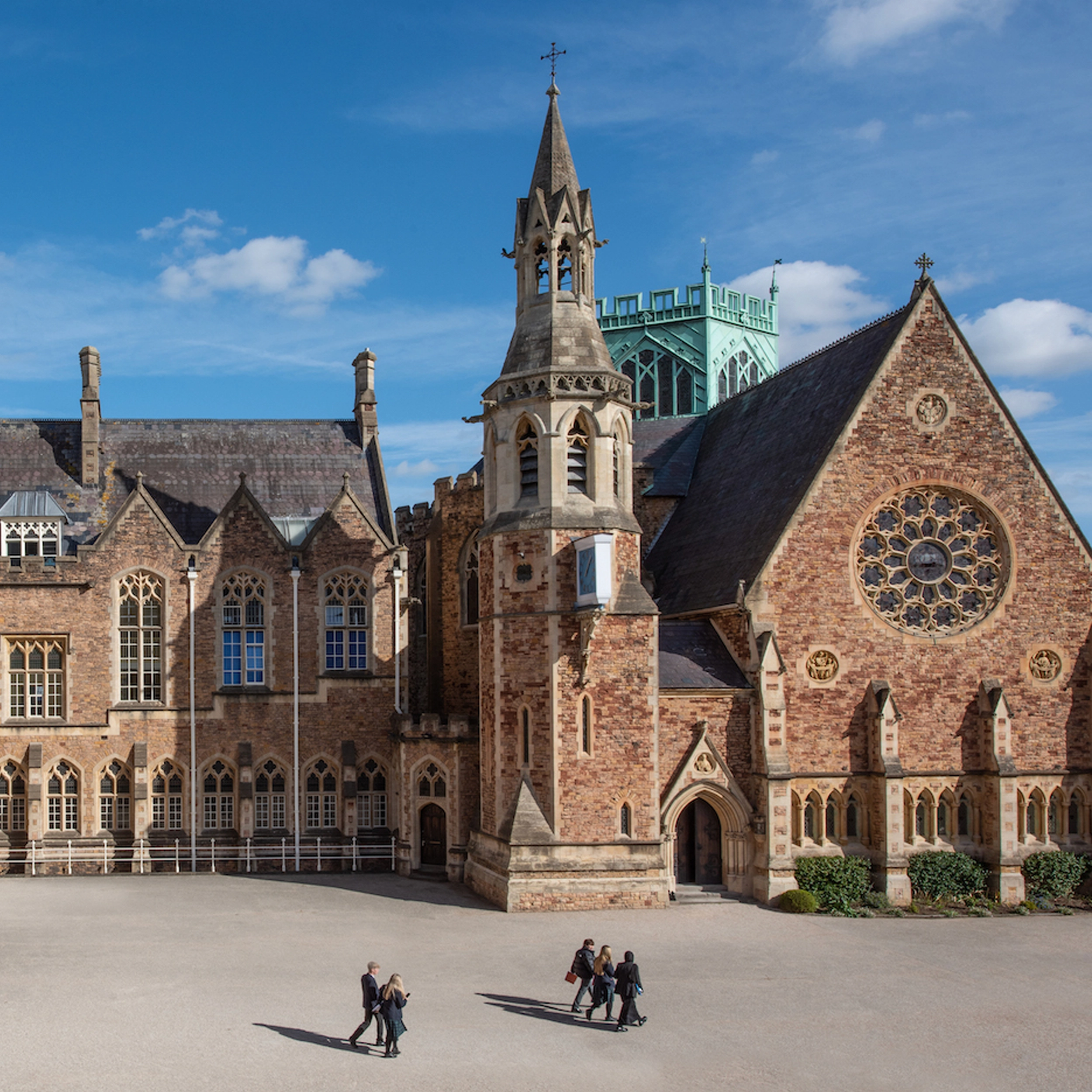 A photograph of a school with children walking across the courtyard